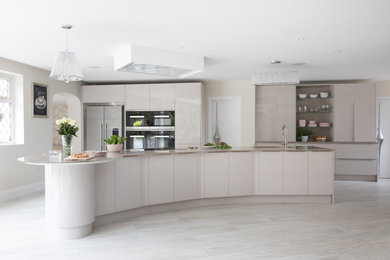 Photo of a large contemporary single-wall open plan kitchen in London with a submerged sink, flat-panel cabinets, beige cabinets, quartz worktops, black appliances, porcelain flooring, an island, grey floors and grey worktops.