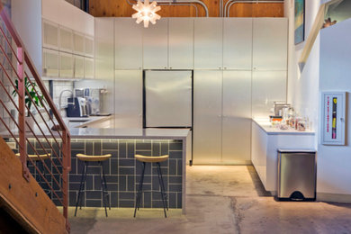Example of a mid-sized urban u-shaped concrete floor and gray floor open concept kitchen design in Los Angeles with an undermount sink, flat-panel cabinets, white cabinets, quartz countertops, multicolored backsplash, window backsplash, white appliances and a peninsula