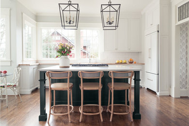 Example of a transitional u-shaped dark wood floor and brown floor kitchen design in Charlotte with shaker cabinets, white cabinets, wood countertops, white backsplash, subway tile backsplash, paneled appliances, an island and beige countertops