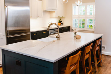 Example of a large transitional galley medium tone wood floor and brown floor eat-in kitchen design in Baltimore with a farmhouse sink, shaker cabinets, white cabinets, quartz countertops, white backsplash, ceramic backsplash, stainless steel appliances, an island and white countertops