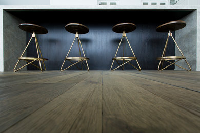 Cette image montre une cuisine design avec un placard à porte plane et un sol en bois brun.