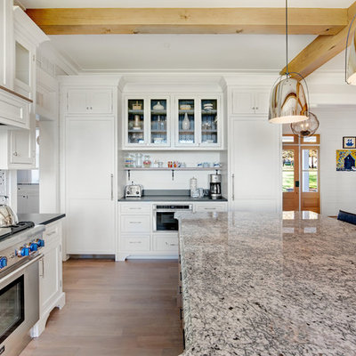 Example of a large farmhouse u-shaped brown floor and medium tone wood floor kitchen design in Baltimore with shaker cabinets, white cabinets, mosaic tile backsplash, paneled appliances, an island, a farmhouse sink and granite countertops