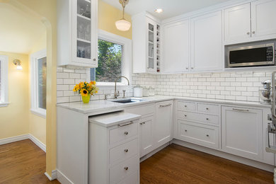 Enclosed kitchen - small traditional u-shaped medium tone wood floor and brown floor enclosed kitchen idea in Boise with an undermount sink, beaded inset cabinets, white cabinets, quartz countertops, white backsplash, subway tile backsplash, paneled appliances, no island and white countertops