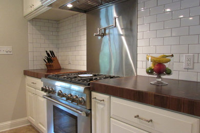 Exempel på ett modernt kök, med en undermonterad diskho, luckor med upphöjd panel, vita skåp, granitbänkskiva, vitt stänkskydd, stänkskydd i tunnelbanekakel, rostfria vitvaror, klinkergolv i porslin och en köksö