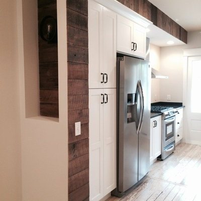 Mid-sized cottage l-shaped light wood floor eat-in kitchen photo in Baltimore with a farmhouse sink, shaker cabinets, white cabinets, solid surface countertops, white backsplash, glass tile backsplash, stainless steel appliances and a peninsula