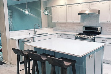 Mid-sized u-shaped kitchen photo in Milwaukee with white cabinets, solid surface countertops, an island, an undermount sink, recessed-panel cabinets, white backsplash, subway tile backsplash, stainless steel appliances and white countertops
