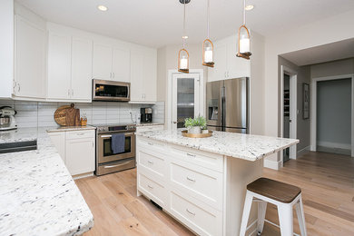 Eat-in kitchen - mid-sized transitional l-shaped light wood floor eat-in kitchen idea with an undermount sink, shaker cabinets, white cabinets, quartz countertops, white backsplash, subway tile backsplash, stainless steel appliances and an island