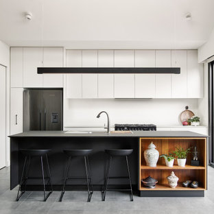 Design ideas for a contemporary galley eat-in kitchen in Melbourne with a drop-in sink, flat-panel cabinets, white cabinets, stainless steel appliances, with island, grey floor, grey benchtop, quartz benchtops, white splashback and cement tiles.