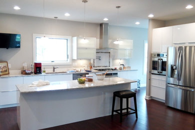 Example of a minimalist vinyl floor kitchen design in Omaha with an undermount sink, flat-panel cabinets, white cabinets, quartz countertops, white backsplash, stainless steel appliances and an island