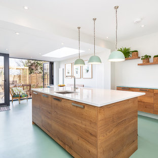 This is an example of a contemporary galley kitchen in London with a submerged sink, flat-panel cabinets, medium wood cabinets, an island, green floors and white worktops.