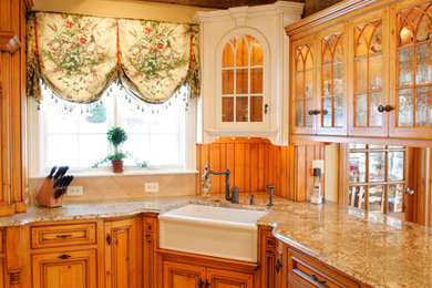 Example of a classic limestone floor kitchen design in Philadelphia with a farmhouse sink, beaded inset cabinets, light wood cabinets, granite countertops and paneled appliances