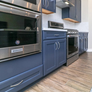 Photo of a mid-sized contemporary l-shaped open plan kitchen in Las Vegas with an undermount sink, recessed-panel cabinets, blue cabinets, quartz benchtops, white splashback, stainless steel appliances, porcelain floors, with island, brown floor and white benchtop.
