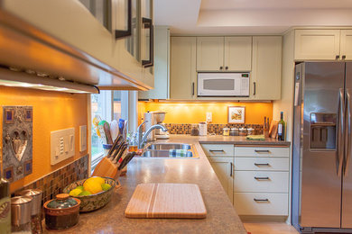 Example of a mid-sized classic u-shaped light wood floor eat-in kitchen design in Other with a drop-in sink, flat-panel cabinets, green cabinets, laminate countertops, multicolored backsplash, glass tile backsplash, stainless steel appliances and a peninsula