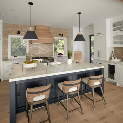 Inspiration for a farmhouse l-shaped light wood floor open concept kitchen remodel in San Francisco with an undermount sink, flat-panel cabinets, white cabinets, quartz countertops, beige backsplash, ceramic backsplash, paneled appliances, an island and white countertops