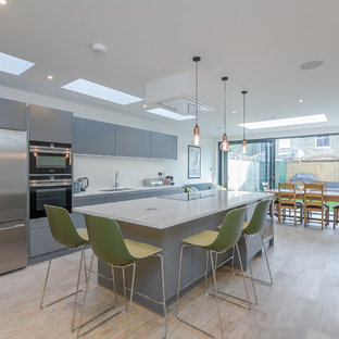 Photo of a medium sized contemporary single-wall kitchen/diner in London with a submerged sink, flat-panel cabinets, grey cabinets, quartz worktops, white splashback, stainless steel appliances, light hardwood flooring, an island, brown floors and white worktops.