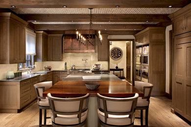 Exempel på ett stort rustikt kök, med en rustik diskho, skåp i shakerstil, skåp i mellenmörkt trä, träbänkskiva, beige stänkskydd, stänkskydd i kalk, rostfria vitvaror, ljust trägolv och en köksö