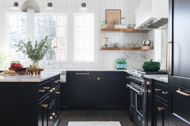 Kitchen - mid-sized transitional l-shaped medium tone wood floor and brown floor kitchen idea in Chicago with a farmhouse sink, shaker cabinets, black cabinets, marble countertops, white backsplash, marble backsplash, paneled appliances and an island
