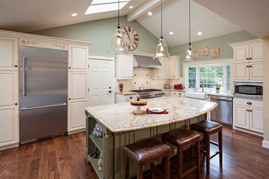 Example of a mid-sized classic l-shaped dark wood floor kitchen design in Seattle with a farmhouse sink, raised-panel cabinets, beige cabinets, stainless steel appliances, an island, granite countertops, ceramic backsplash and white backsplash