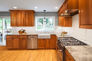 Example of a mid-sized classic u-shaped light wood floor eat-in kitchen design in Seattle with a farmhouse sink, raised-panel cabinets, medium tone wood cabinets, white backsplash, ceramic backsplash and stainless steel appliances