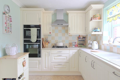 This is an example of a medium sized farmhouse l-shaped kitchen/diner in Essex with a double-bowl sink, shaker cabinets, white cabinets, quartz worktops, multi-coloured splashback, ceramic splashback, stainless steel appliances and no island.