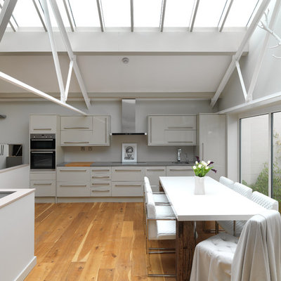 Eat-in kitchen - mid-sized modern medium tone wood floor and beige floor eat-in kitchen idea in London with an undermount sink, flat-panel cabinets, gray cabinets, stainless steel appliances and no island