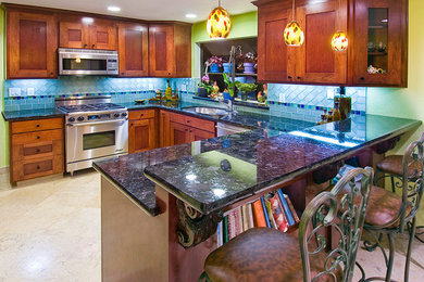 Exempel på ett mellanstort, avskilt eklektiskt u-kök, med skåp i shakerstil, skåp i mellenmörkt trä, granitbänkskiva, en halv köksö, en undermonterad diskho, blått stänkskydd, stänkskydd i keramik, rostfria vitvaror och travertin golv
