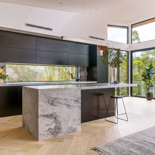 Photo of a large modern kitchen in Sydney with black cabinets, marble benchtops, marble splashback, black appliances and with island.