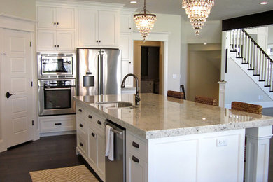Eat-in kitchen - traditional l-shaped dark wood floor eat-in kitchen idea in Salt Lake City with an island, flat-panel cabinets, white cabinets, granite countertops, white backsplash, porcelain backsplash, stainless steel appliances and an undermount sink