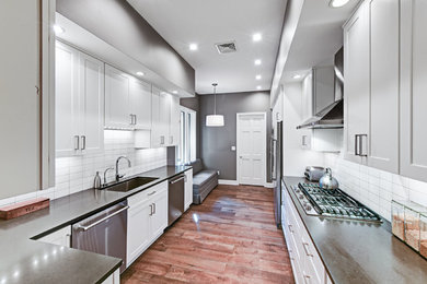 Example of a mid-sized trendy galley medium tone wood floor and brown floor enclosed kitchen design in Phoenix with an undermount sink, shaker cabinets, white cabinets, soapstone countertops, white backsplash, subway tile backsplash, stainless steel appliances and no island