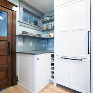 Design ideas for a scandinavian kitchen in Minneapolis with a farmhouse sink, shaker cabinets, white cabinets, recycled glass benchtops, white splashback, subway tile splashback, panelled appliances, light hardwood floors and black benchtop.