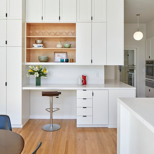 Inspiration for a midcentury kitchen in San Francisco with an integrated sink, flat-panel cabinets, white cabinets, stainless steel benchtops, white splashback, stone slab splashback, stainless steel appliances, light hardwood floors and with island.