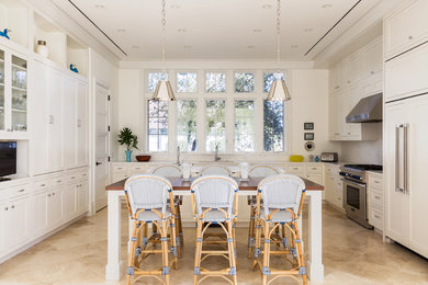 Eat-in kitchen - large transitional u-shaped limestone floor and beige floor eat-in kitchen idea in Miami with shaker cabinets, white cabinets, white backsplash, stone slab backsplash, stainless steel appliances and an island