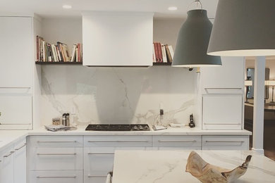 Immagine di un cucina con isola centrale contemporaneo di medie dimensioni con ante lisce, ante bianche, top in superficie solida, paraspruzzi bianco, paraspruzzi in lastra di pietra e top bianco