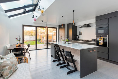 Foto di una cucina minimal di medie dimensioni con ante lisce, ante nere, top in marmo, parquet chiaro e pavimento bianco