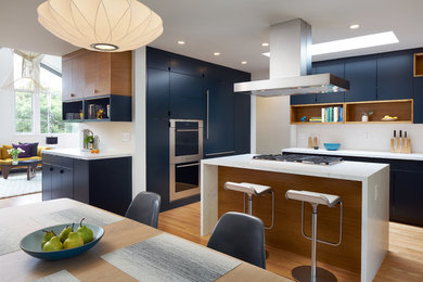 Example of a mid-sized 1960s u-shaped light wood floor and beige floor eat-in kitchen design in San Francisco with flat-panel cabinets, blue cabinets, quartzite countertops, paneled appliances, an island, white countertops, white backsplash, subway tile backsplash and an undermount sink