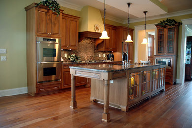 Elegant l-shaped medium tone wood floor eat-in kitchen photo in Indianapolis with an undermount sink, raised-panel cabinets, medium tone wood cabinets, granite countertops and stainless steel appliances