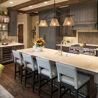 Ispirazione per una cucina classica di medie dimensioni con lavello stile country, ante con riquadro incassato, ante in legno bruno, top in pietra calcarea, elettrodomestici in acciaio inossidabile, parquet scuro, paraspruzzi beige, pavimento marrone e paraspruzzi in pietra calcarea