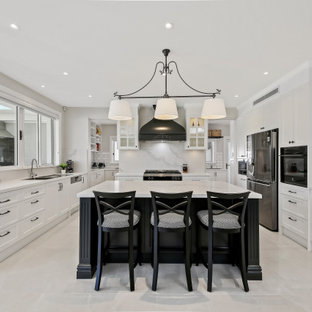 Inspiration for a large transitional u-shaped eat-in kitchen in Sydney with a double-bowl sink, beaded inset cabinets, white cabinets, quartz benchtops, white splashback, subway tile splashback, stainless steel appliances, ceramic floors, with island, white floor and white benchtop.