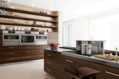 This is an example of a large contemporary single-wall kitchen in Vancouver with flat-panel cabinets, dark wood cabinets, composite countertops, beige splashback, stone tiled splashback, stainless steel appliances, porcelain flooring and an island.