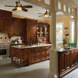 Idee per un'ampia cucina vittoriana con ante di vetro, ante in legno scuro, top in superficie solida, elettrodomestici in acciaio inossidabile, pavimento con piastrelle in ceramica, isola, lavello da incasso, paraspruzzi beige e paraspruzzi con piastrelle in ceramica