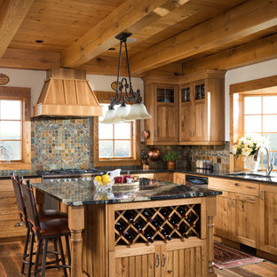 This is an example of a traditional l-shaped eat-in kitchen in Calgary with medium wood cabinets, stainless steel appliances, with island, an undermount sink, recessed-panel cabinets, multi-coloured splashback, medium hardwood floors and slate splashback.