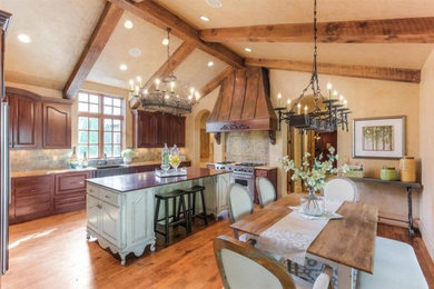 Large mountain style l-shaped light wood floor eat-in kitchen photo in Nashville with an undermount sink, raised-panel cabinets, beige cabinets, wood countertops, green backsplash, ceramic backsplash, stainless steel appliances and an island