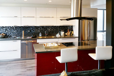 Example of a large minimalist single-wall light wood floor eat-in kitchen design in Los Angeles with a single-bowl sink, flat-panel cabinets, white cabinets, black backsplash, mosaic tile backsplash, stainless steel appliances and an island