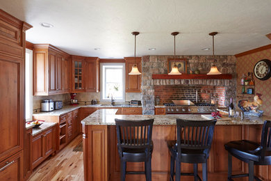 Foto på ett mellanstort vintage kök, med en dubbel diskho, luckor med upphöjd panel, skåp i mellenmörkt trä, granitbänkskiva, flerfärgad stänkskydd, stänkskydd i tegel, rostfria vitvaror, ljust trägolv och en halv köksö