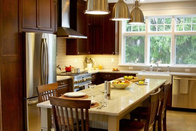 Example of a mid-sized transitional l-shaped ceramic tile eat-in kitchen design in Chicago with recessed-panel cabinets, brown cabinets, quartzite countertops, gray backsplash, subway tile backsplash, stainless steel appliances, an island and a farmhouse sink