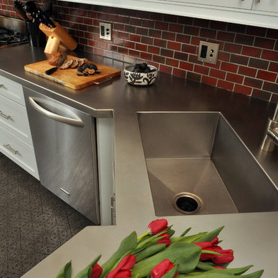 Example of a mid-sized trendy galley concrete floor eat-in kitchen design in Chicago with stainless steel appliances, stainless steel countertops, an integrated sink, shaker cabinets, white cabinets, red backsplash and subway tile backsplash