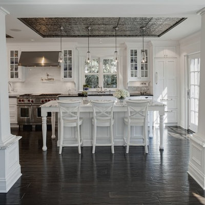Elegant kitchen photo in Chicago with stainless steel appliances, glass-front cabinets, white cabinets, white backsplash and subway tile backsplash