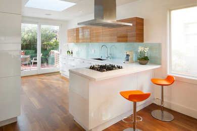 Inspiration for a large modern l-shaped dark wood floor eat-in kitchen remodel in San Francisco with an undermount sink, flat-panel cabinets, white cabinets, solid surface countertops, blue backsplash, glass tile backsplash, stainless steel appliances and a peninsula