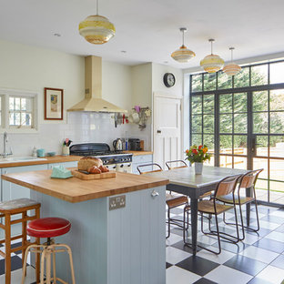 Immagine di una cucina ad ambiente unico eclettica con ante in stile shaker, ante blu, top in legno, isola, lavello a doppia vasca, paraspruzzi bianco, paraspruzzi con piastrelle diamantate e pavimento multicolore
