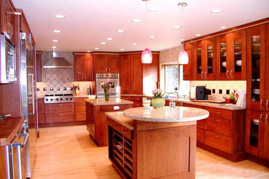 Example of a large classic l-shaped light wood floor enclosed kitchen design in Other with an undermount sink, glass-front cabinets, medium tone wood cabinets, granite countertops, stainless steel appliances and two islands